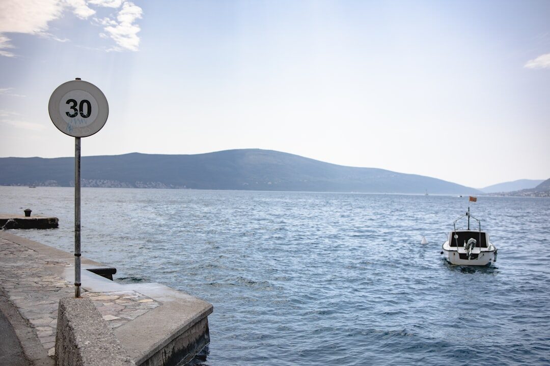 Documentary photographer taking a photo of an elderly Croatian fisherman mending nets on a stone pier