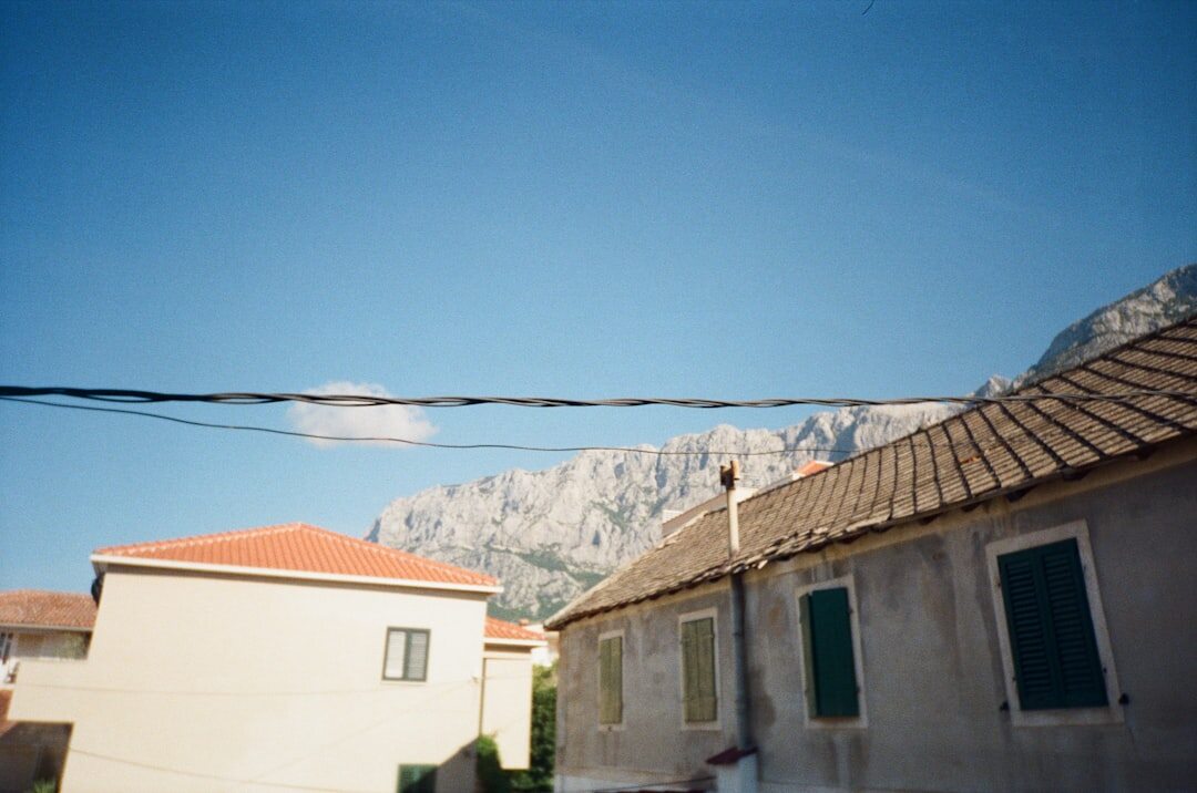 Elderly Croatian woman making lace in front of her stone house